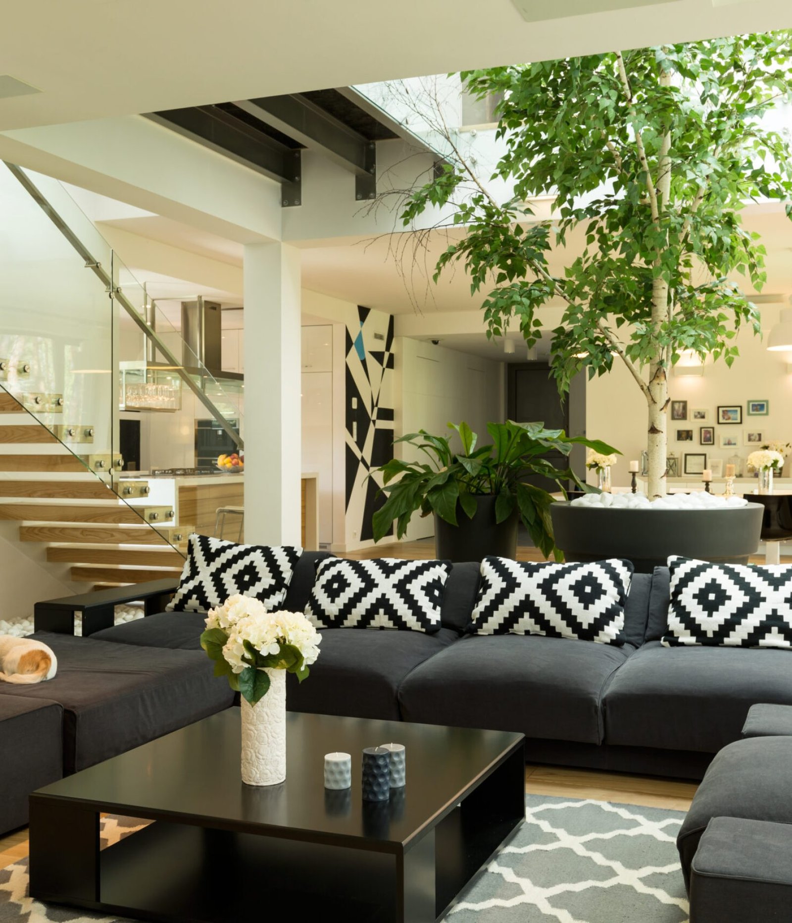 Living room with black sofa, patterned pillowes and coffee table open to the staircase